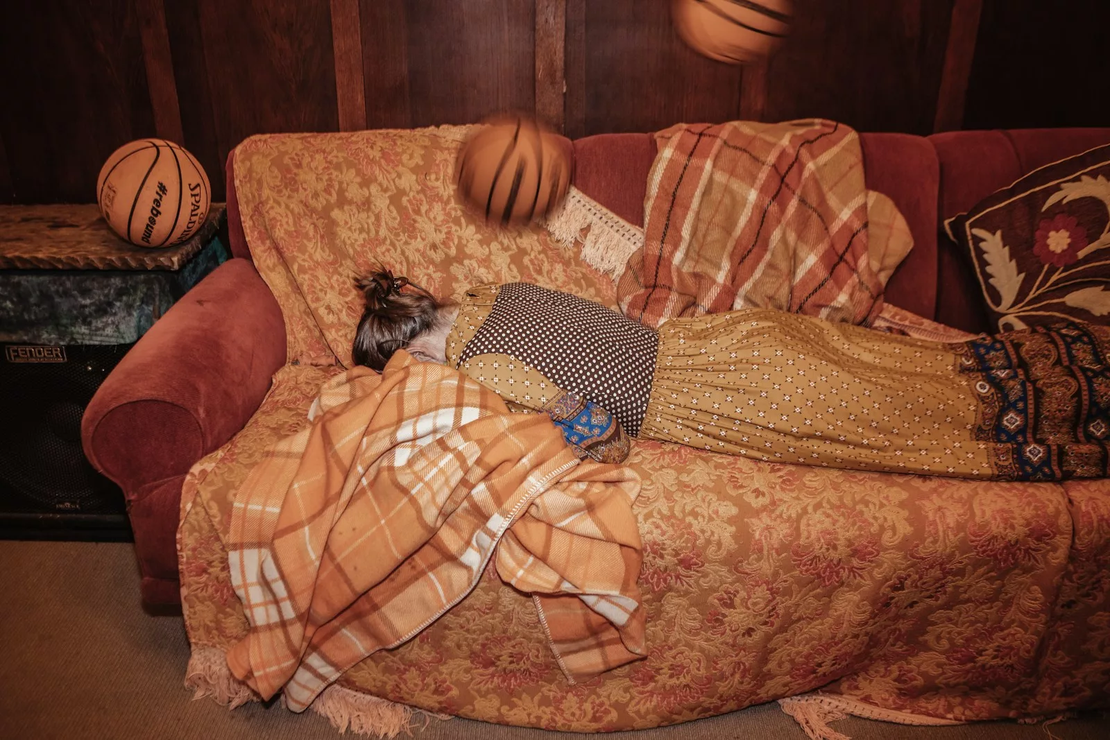 a person laying on a couch covered in blankets